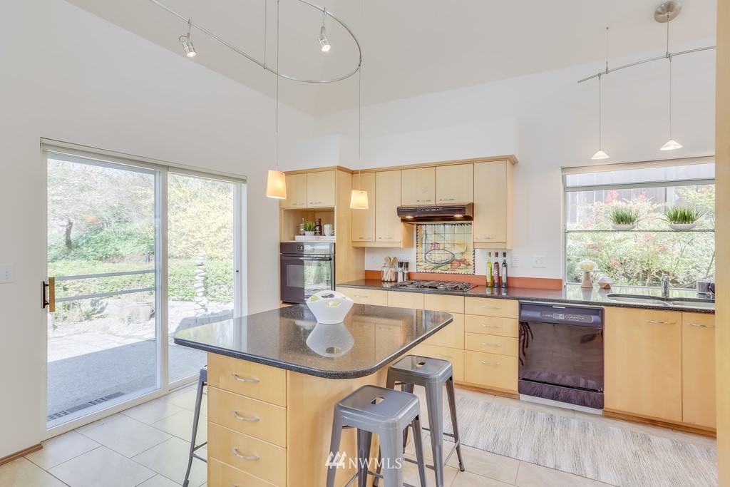 5006 Northeast 18th Court Renton, WA 98059 - Photo 14 of 35 a kitchen with stainless steel appliances granite countertop a stove a refrigerator a sink a dining table and chairs with wooden floor