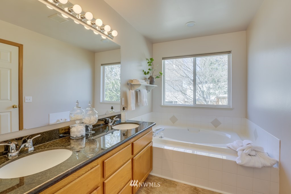 5006 Northeast 18th Court Renton, WA 98059 - Photo 22 of 35 a bathroom with a granite countertop tub a double vanity sink a mirror a window and a shower