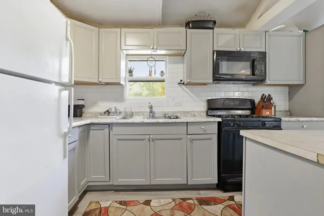 a kitchen with stainless steel appliances granite countertop a sink a refrigerator a stove and white cabinets with wooden floor