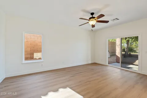 an empty room with wooden floor fan and windows