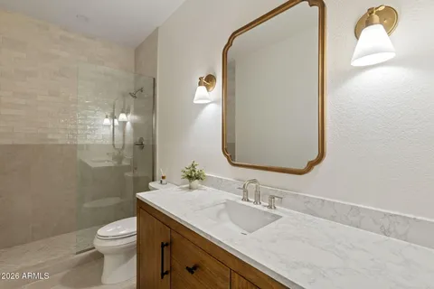 a bathroom with a granite countertop toilet sink and mirror