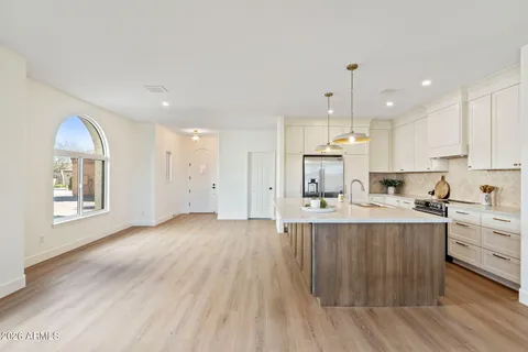 a large kitchen with stainless steel appliances refrigerator a stove top oven with wooden floors