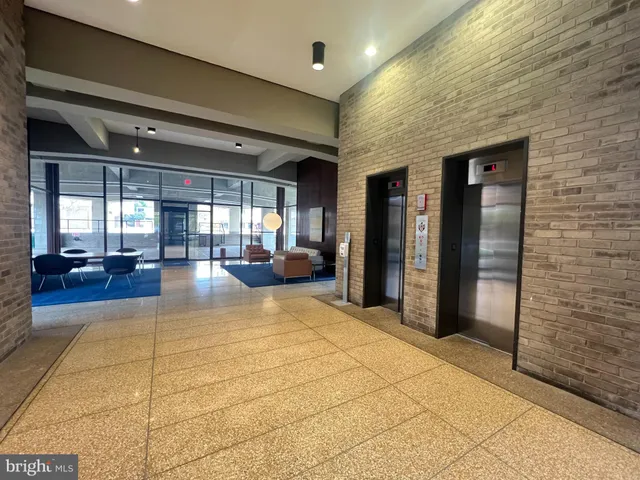 a front view of a building with glass windows and plants