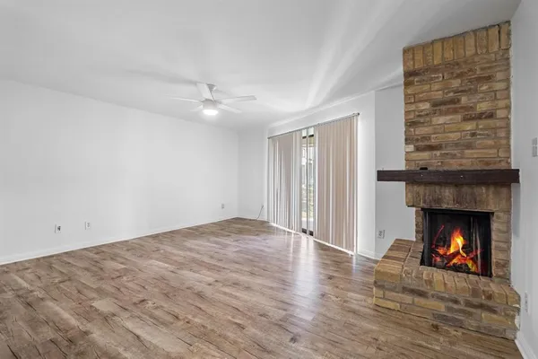 a view of an empty room with wooden floor fireplace and a window