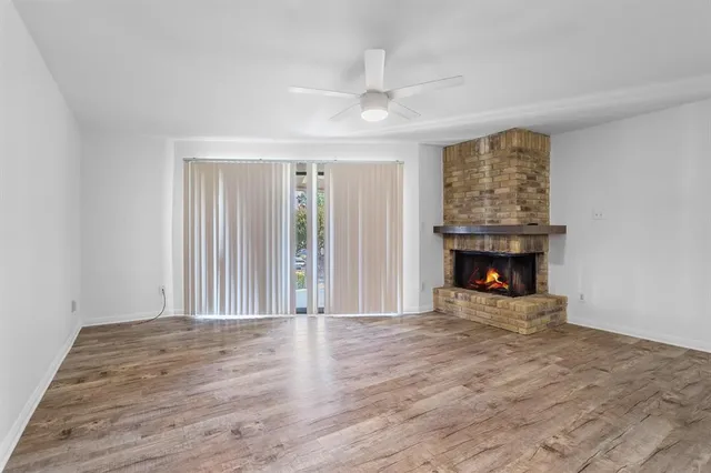 an empty room with wooden floor fireplace and windows