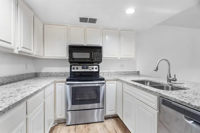 a kitchen with white cabinets stainless steel appliances and sink