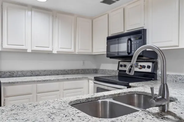a kitchen with granite countertop a sink stainless steel appliances and cabinets