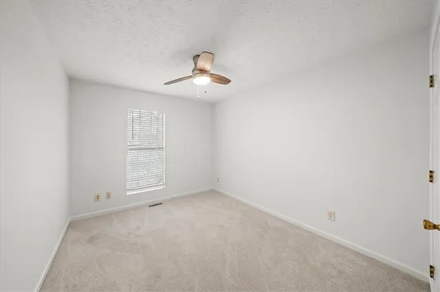 an empty room with windows and chandelier fan