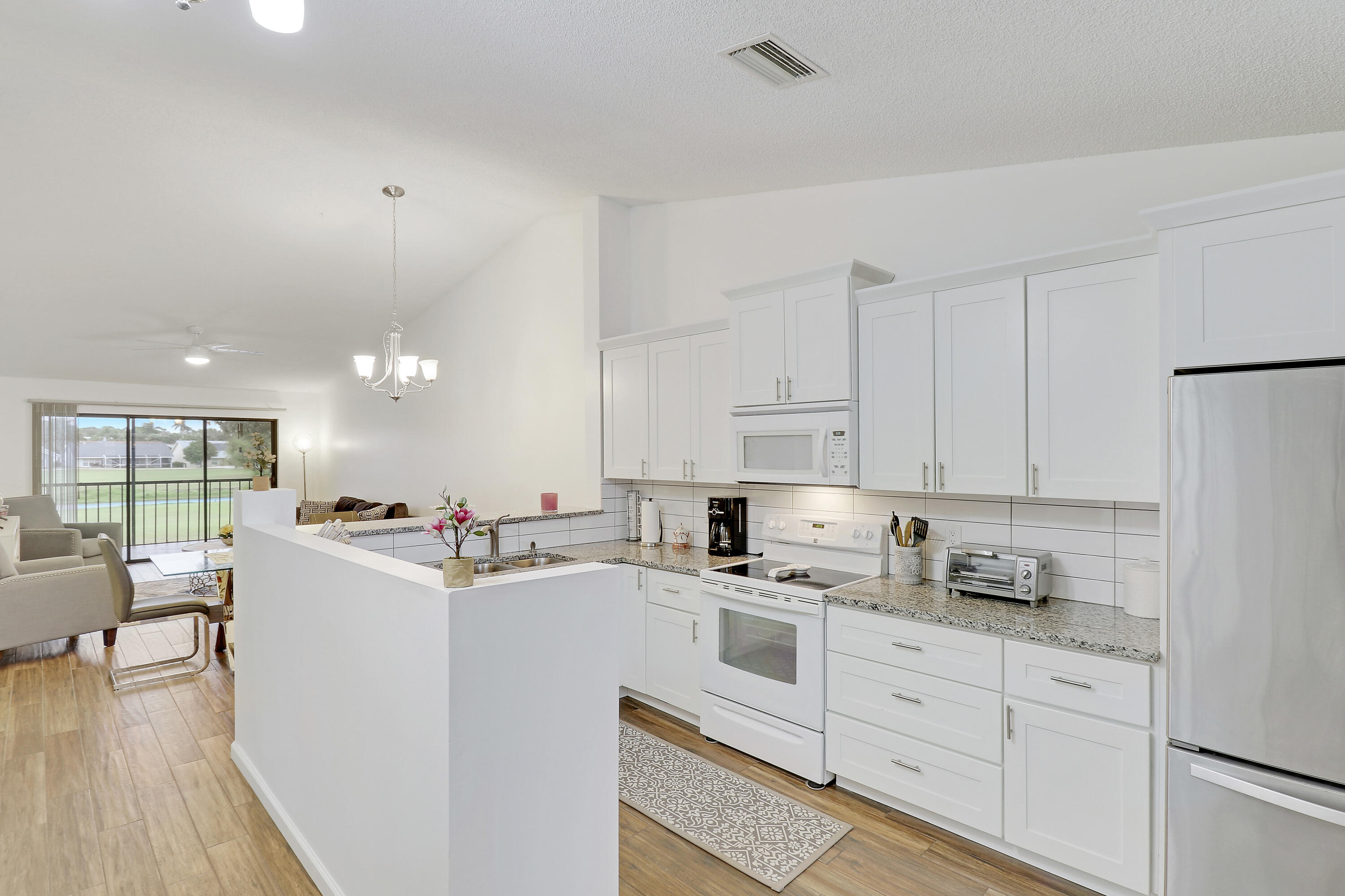 1112 Keystone Drive, Unit A Jupiter, FL 33458 - Photo 14 of 41 a kitchen with granite countertop white cabinets and white appliances