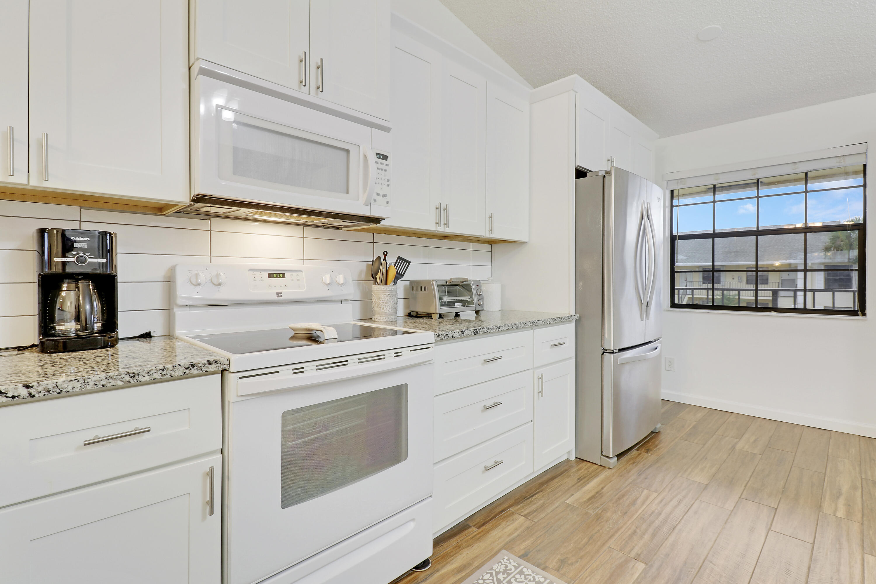 1112 Keystone Drive, Unit A Jupiter, FL 33458 - Photo 16 of 41 a kitchen with granite countertop white cabinets and white appliances