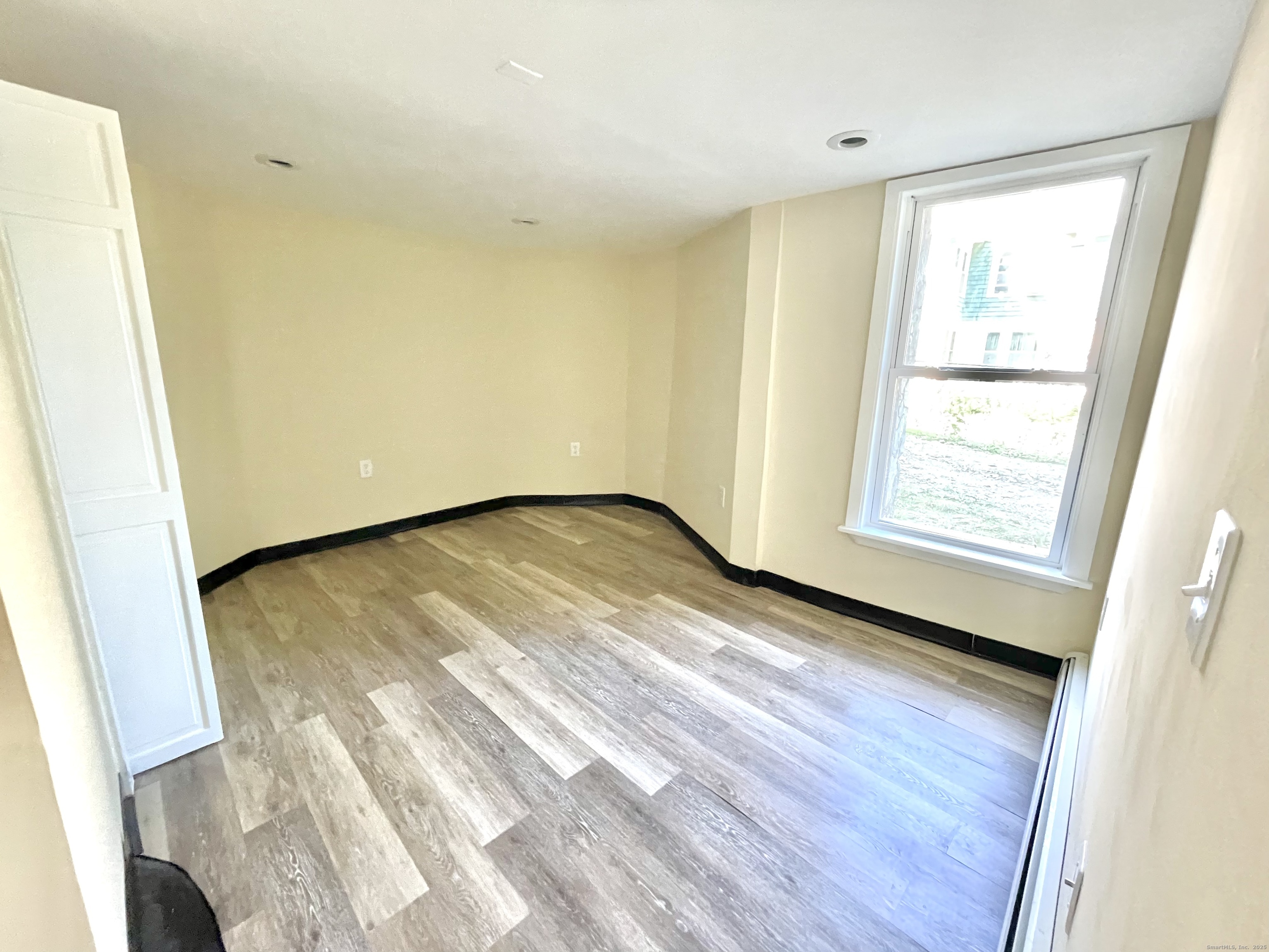 129 Highland Avenue, Unit B Waterbury, CT 06708 - Photo 12 of 17 a view of an empty room with wooden floor and a window
