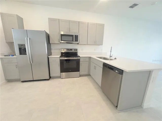 a kitchen with stainless steel appliances granite countertop a refrigerator a stove a sink a stove a microwave and island