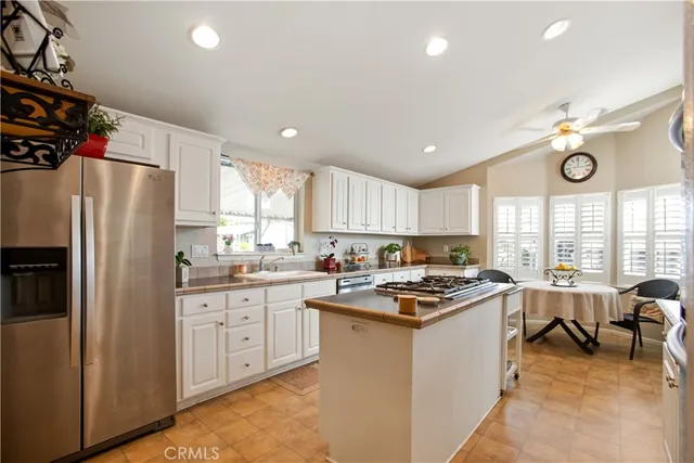 a kitchen with stainless steel appliances granite countertop a stove top oven a refrigerator a sink and dishwasher with white cabinets