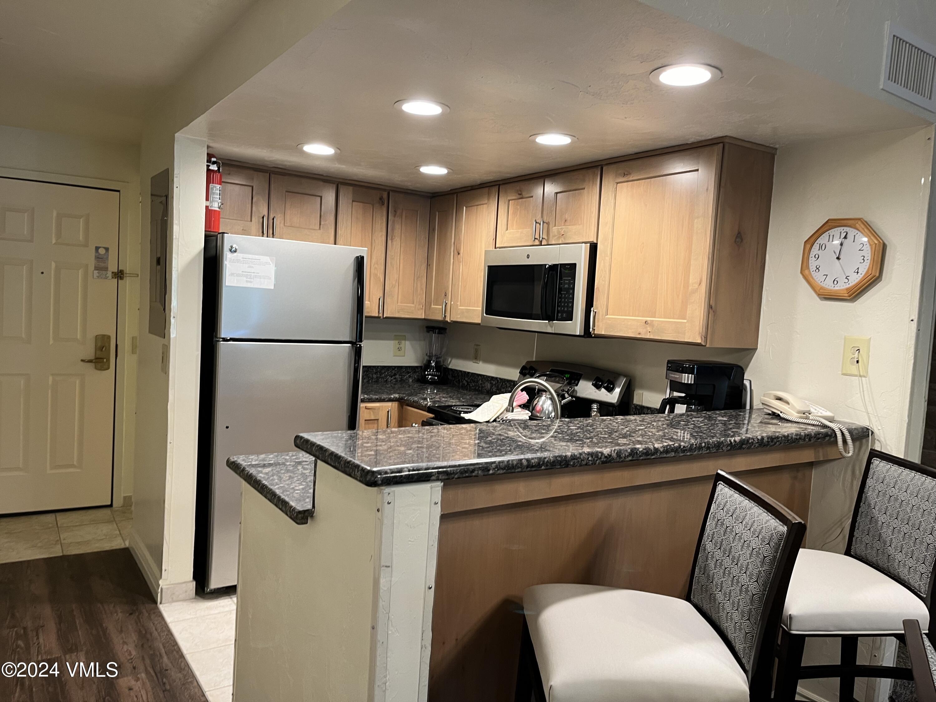 a kitchen with a refrigerator a stove a microwave oven with a dining table and chairs