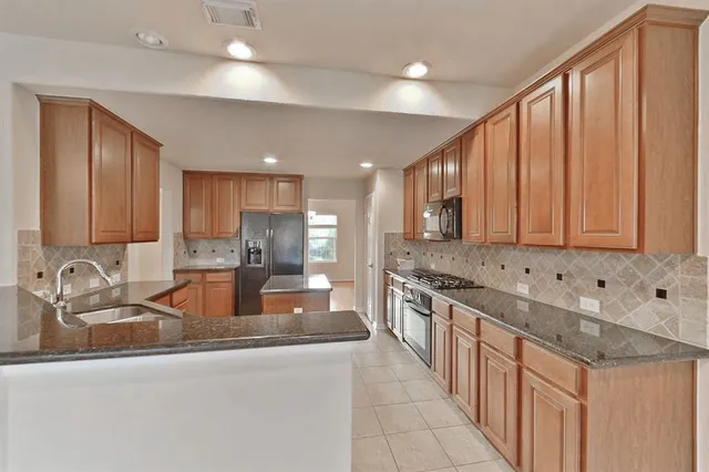a kitchen with stainless steel appliances granite countertop a sink stove and cabinets