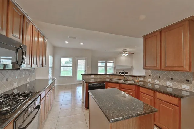 a kitchen with stainless steel appliances granite countertop a stove a sink and a microwave