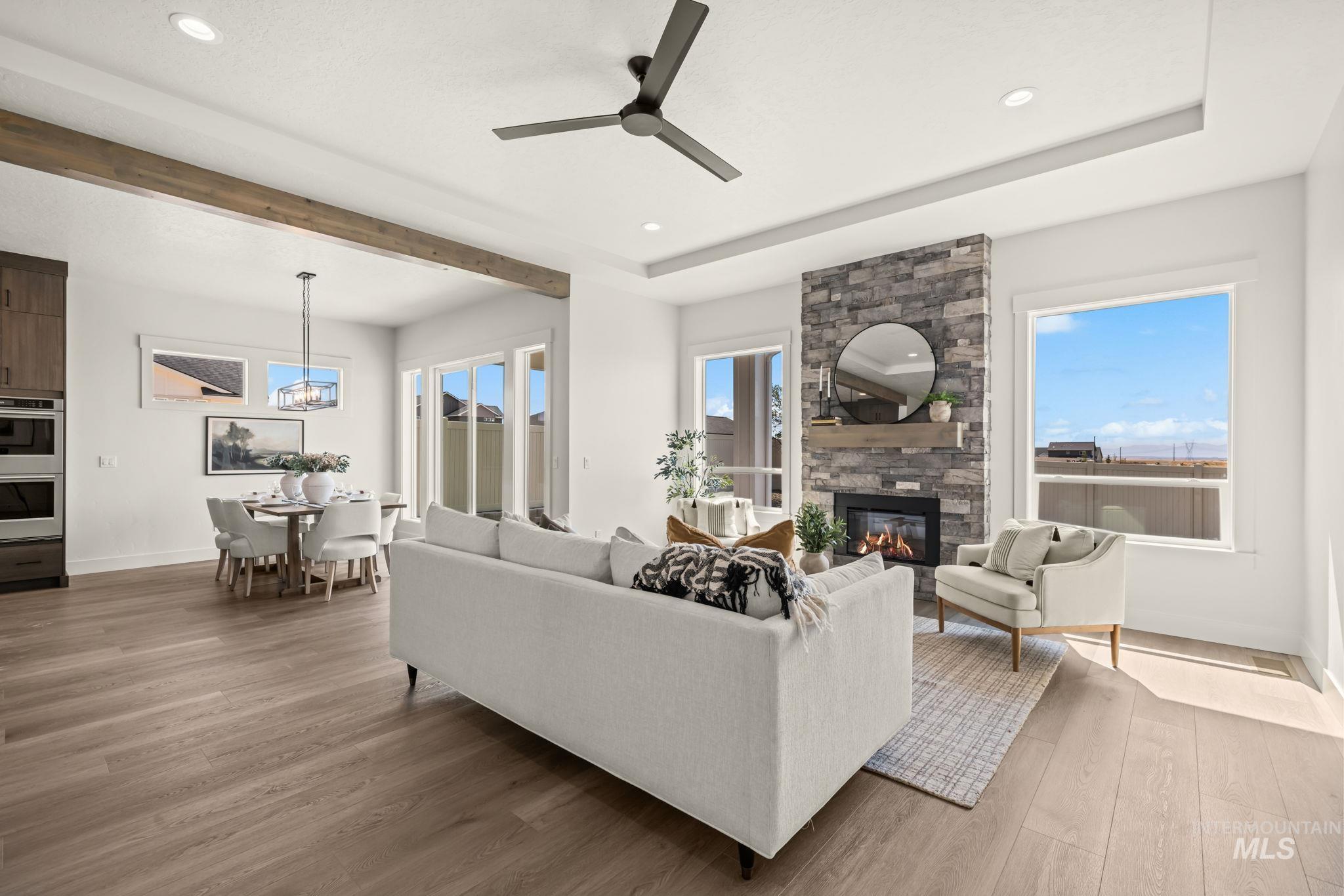 345 South Strut Way Boise, ID 83716 - Photo 19 of 50 Wood-finish flooring throughout, tray ceiling with recessed lighting, stone-clad fireplace with mantel, and large windows providing ample natural light