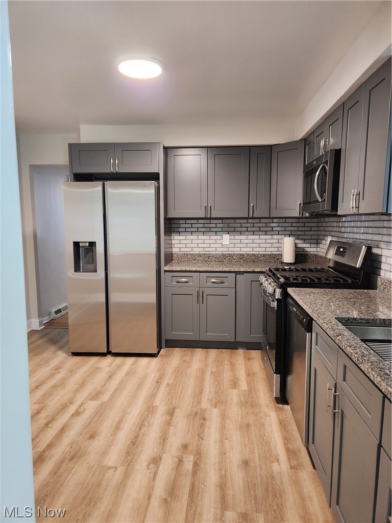 4660 West Farnhurst Road South Euclid, OH 44121 - Photo 5 of 17 Kitchen with refrigerator, stove, gray cabinets, light hardwood / wood-style flooring, and stone counters