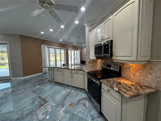 a large kitchen with stainless steel appliances granite countertop a refrigerator a stove a sink and a microwave