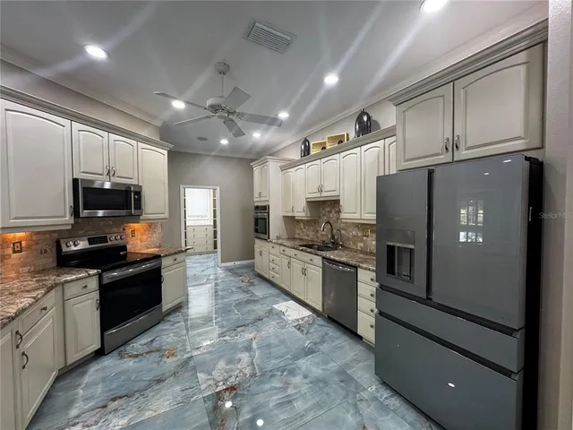 a large kitchen with stainless steel appliances granite countertop a refrigerator and a stove