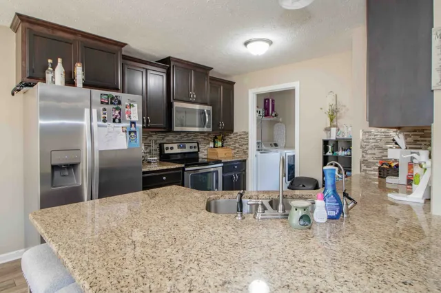 a kitchen with stainless steel appliances kitchen island granite countertop a refrigerator and a sink