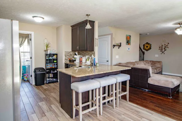 a kitchen with granite countertop a dining table chairs and wooden floor