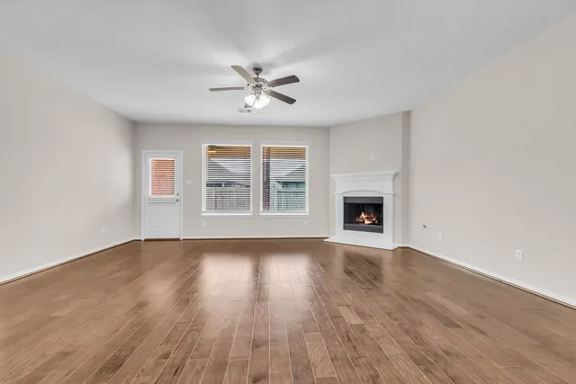 a view of an empty room with wooden floor and a window