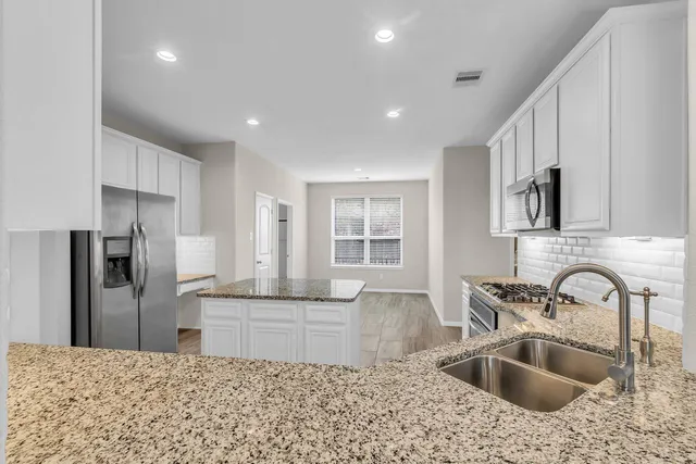 a kitchen with stainless steel appliances granite countertop a sink and a refrigerator