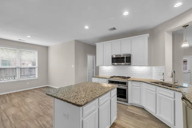 a kitchen with a sink stove cabinets and microwave