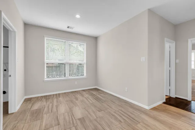 a view of an empty room with wooden floor and a window