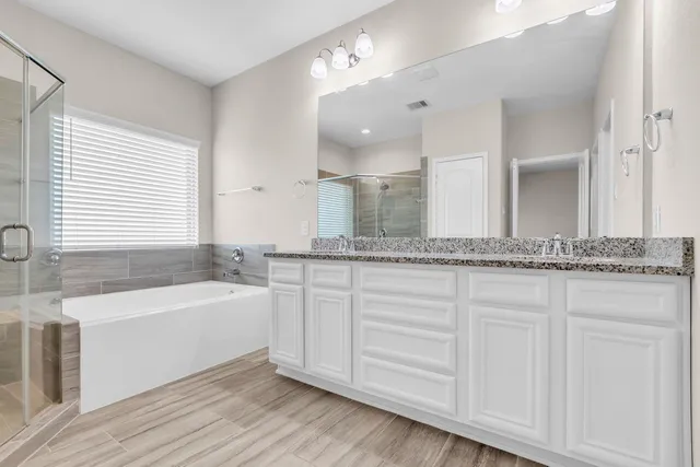 a bathroom with a tub a double vanity sink and a mirror