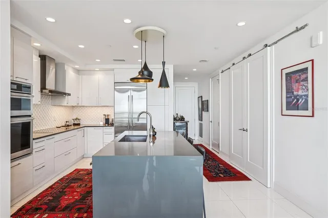 a kitchen with stainless steel appliances granite countertop a refrigerator a sink a stove and oven