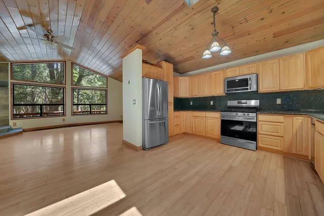 a kitchen with stainless steel appliances granite countertop a sink a stove top oven and wooden floors
