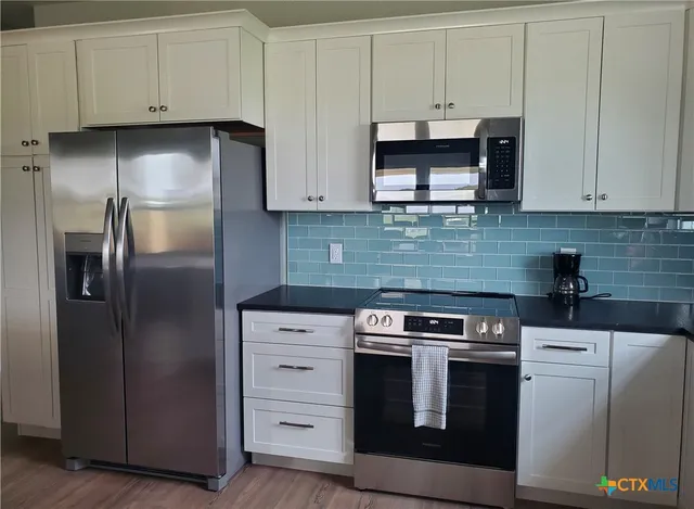 a kitchen with stainless steel appliances granite countertop a refrigerator stove and sink