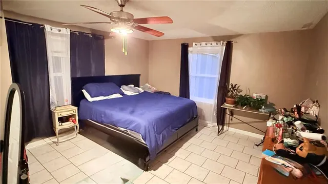 a bedroom with a bed dresser flowerpot and window