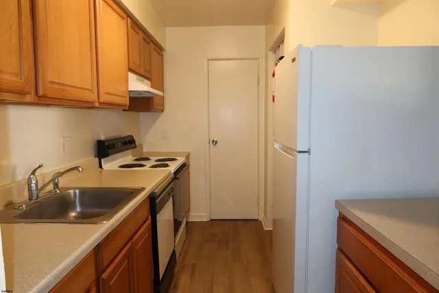 a kitchen with stainless steel appliances a sink dishwasher stove and cabinets with wooden floor