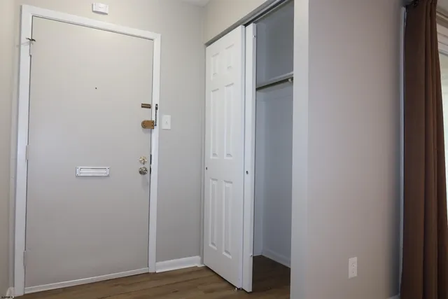 a view of an empty room with wooden floor and a fireplace