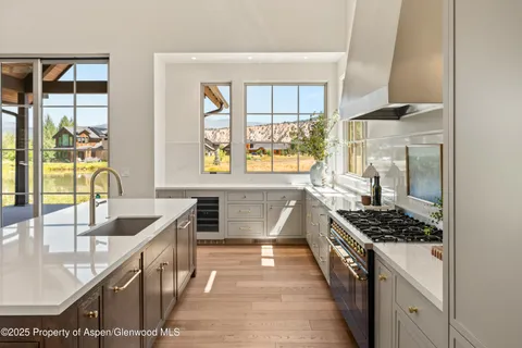 a kitchen with stainless steel appliances kitchen island a large window in it and white cabinets