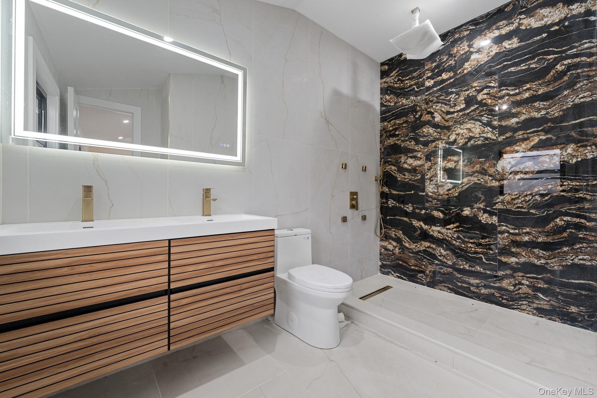 116-20 194th Street Queens, NY 11412 - Photo 18 of 27 Bathroom with a marble finish shower, double vanity, tile walls, light marble finish flooring, and vaulted ceiling