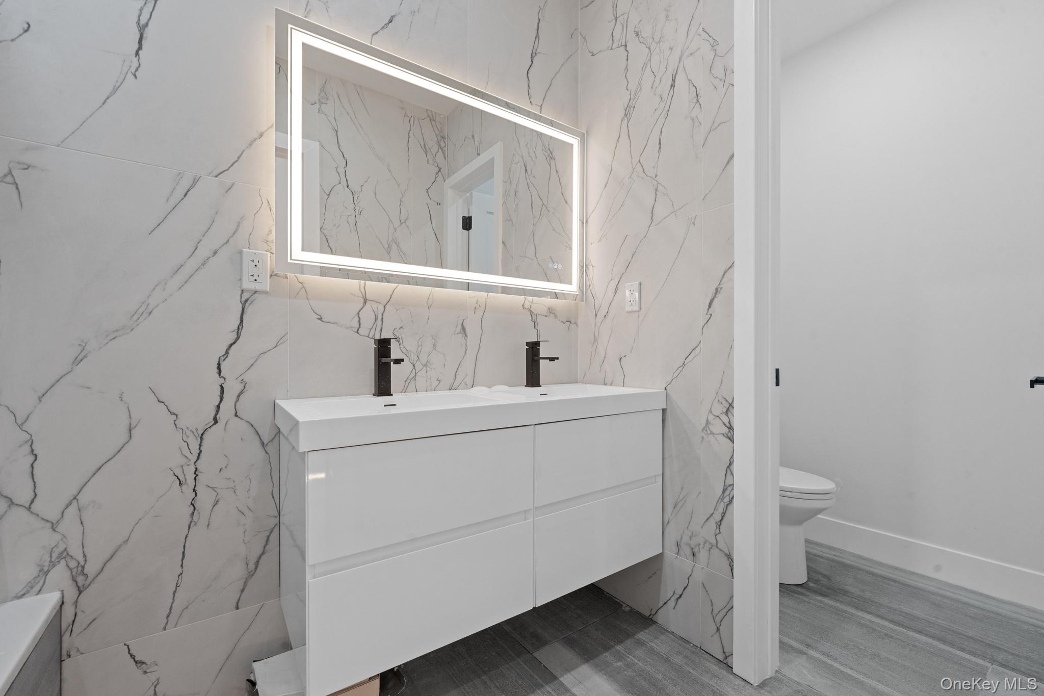 116-20 194th Street Queens, NY 11412 - Photo 22 of 27 Full bath featuring double vanity, stone wall, and tile walls