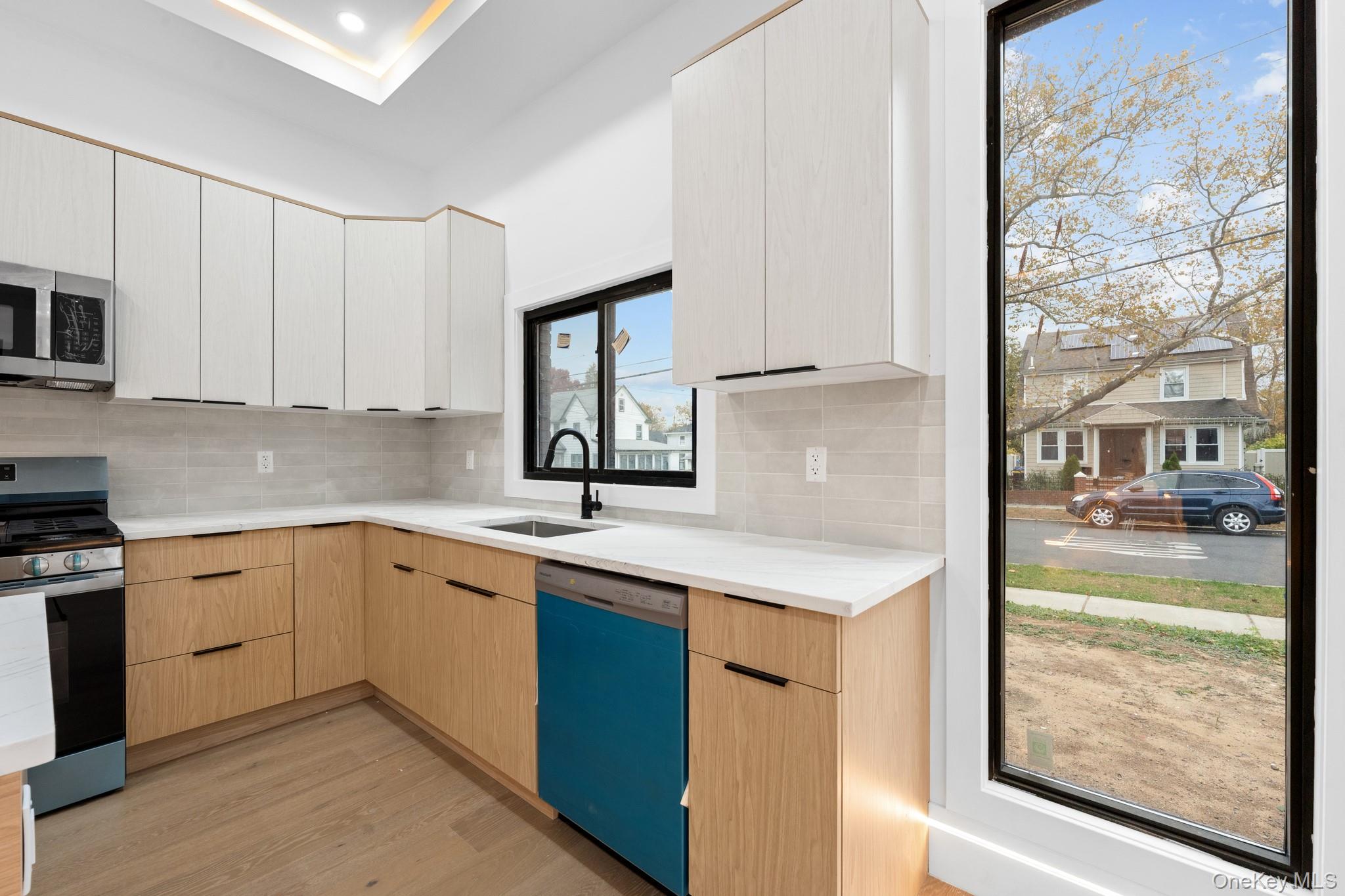 116-20 194th Street Queens, NY 11412 - Photo 6 of 27 Kitchen featuring light brown cabinetry, appliances with stainless steel finishes, light wood-type flooring, modern cabinets, and backsplash