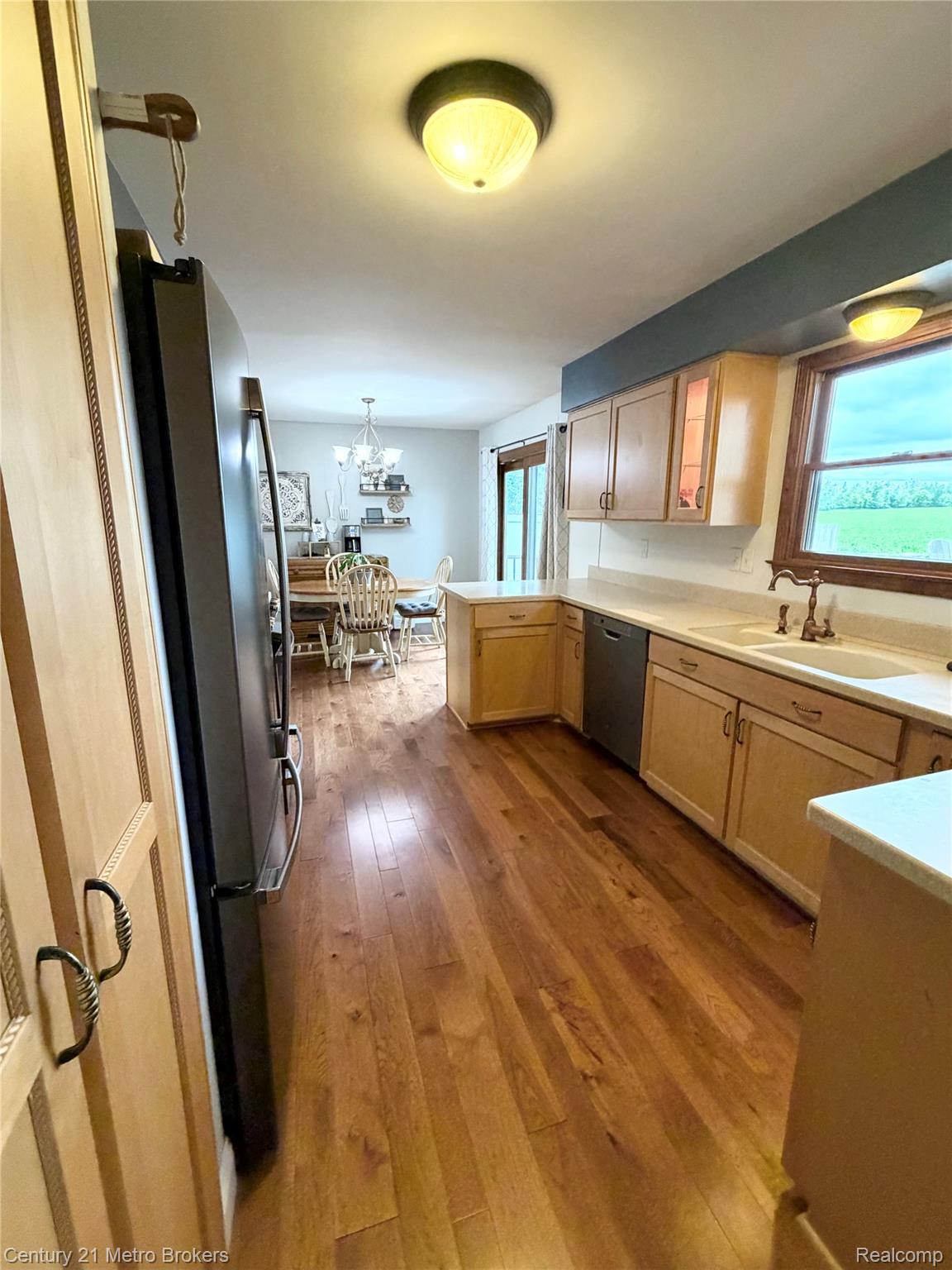 3259 North Seymour Road Flushing, MI 48433 - Photo 17 of 49 Kitchen featuring wood-finish flooring, light wood cabinetry, a double basin sink, and integrated stainless steel appliances