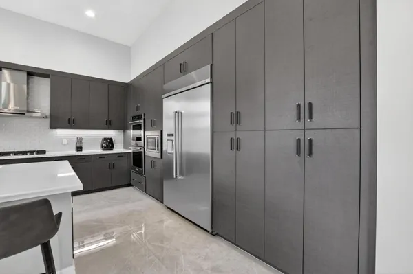 a kitchen with stainless steel appliances granite countertop a sink a stove a refrigerator and chairs