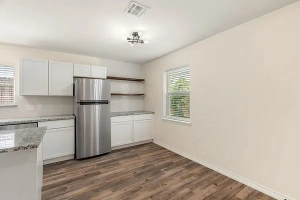 a kitchen with stainless steel appliances a refrigerator and a hard wood floor
