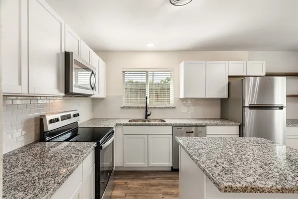 a kitchen with stainless steel appliances granite countertop a sink stove and refrigerator