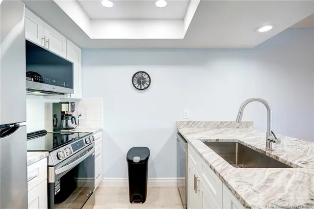 a view of kitchen with kitchen island granite countertop a stove top oven a sink dishwasher a dining table and chairs with wooden floor