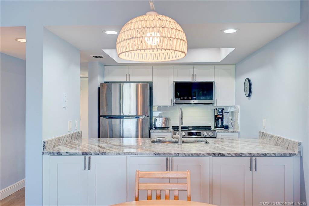 40 Northeast Plantation Road, Unit 209 Stuart, FL 34996 - Photo 7 of 36 a kitchen with stainless steel appliances granite countertop a sink and a refrigerator
