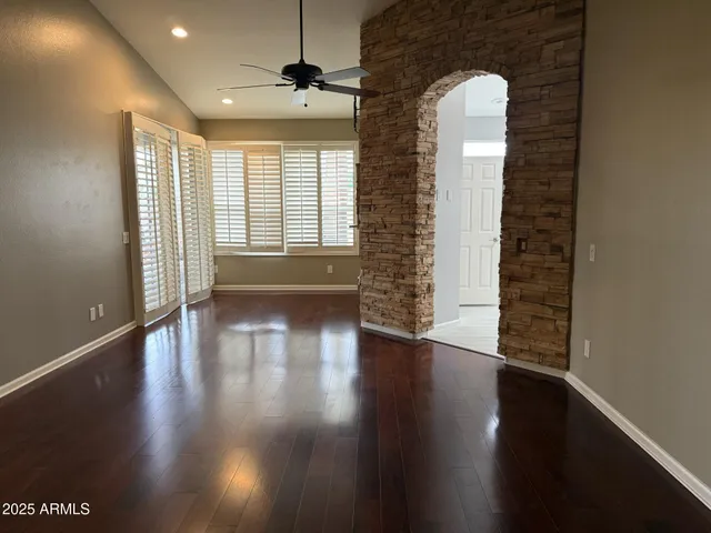 an empty room with wooden floor chandelier and windows