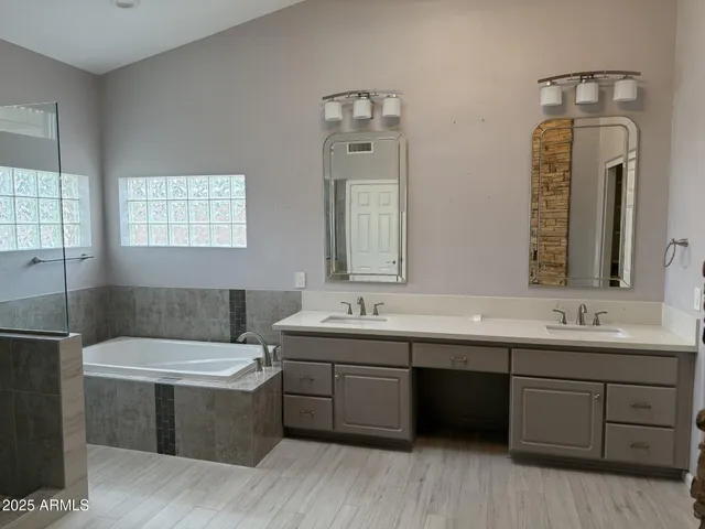 a bathroom with a double vanity sink a mirror and a bathtub