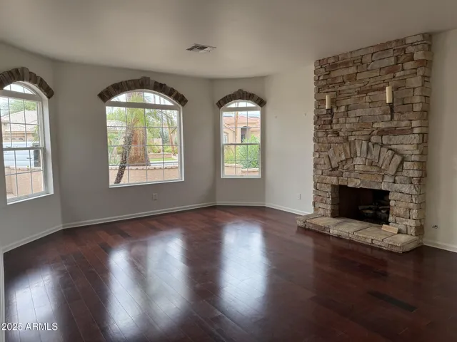 a view of an empty room with wooden floor and a fireplace